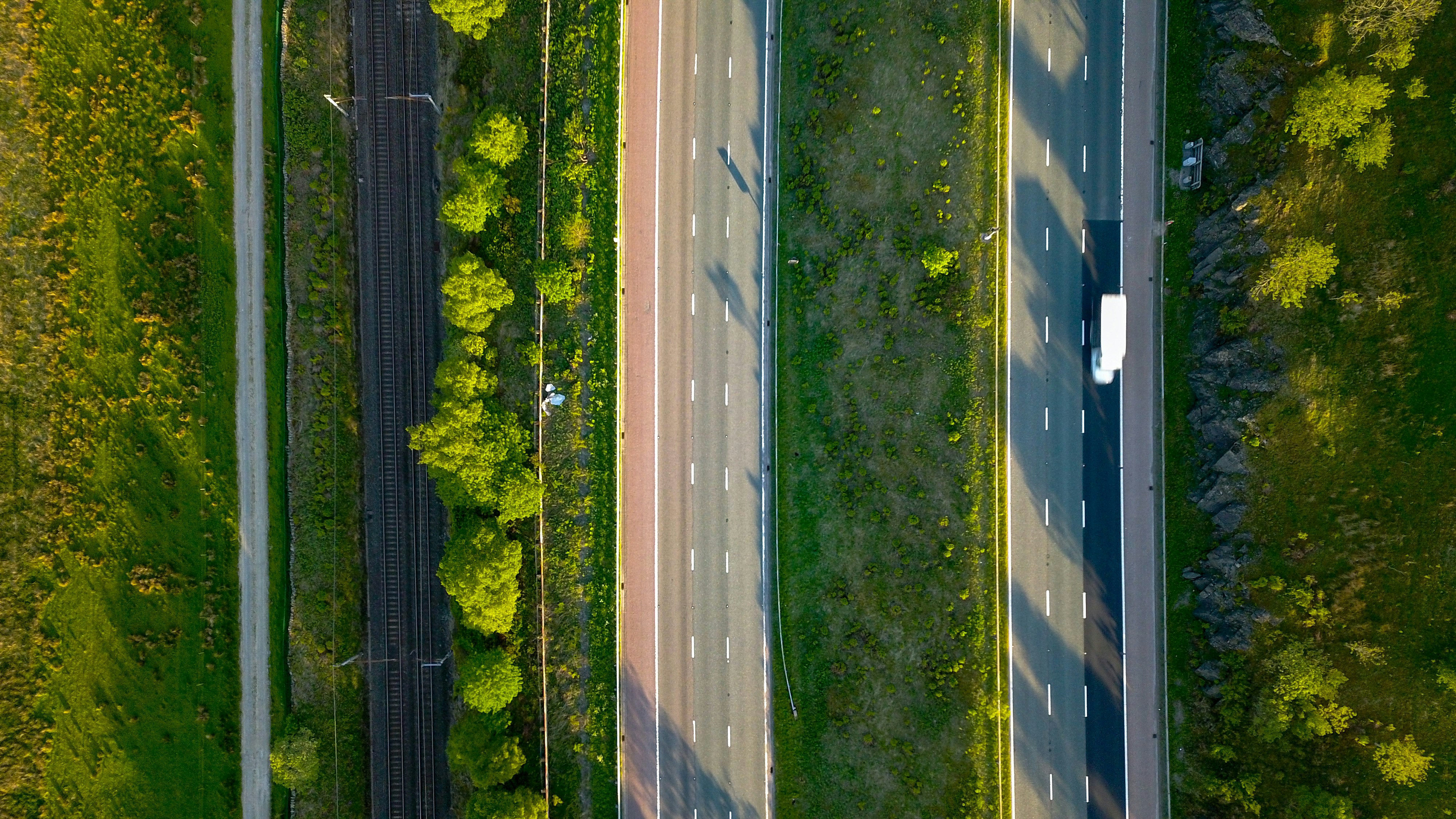 Aerial photo of a footpath, railway tracks, and two roads vertically parallel to each other