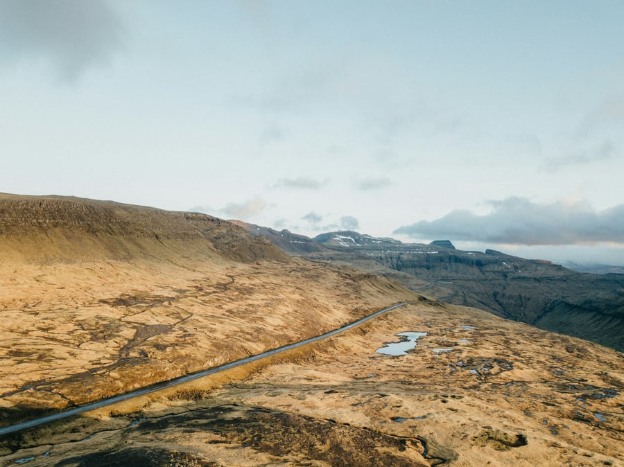A long road stretching across a treeless, grassy mountain range
