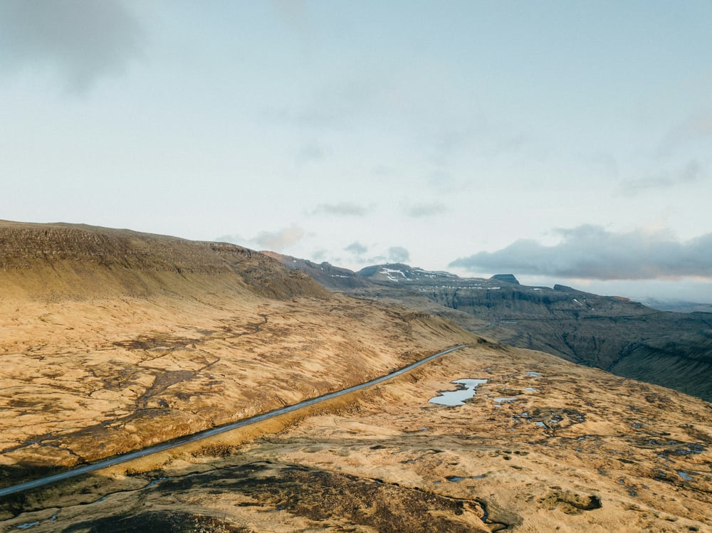A long road stretching across a treeless, grassy mountain range