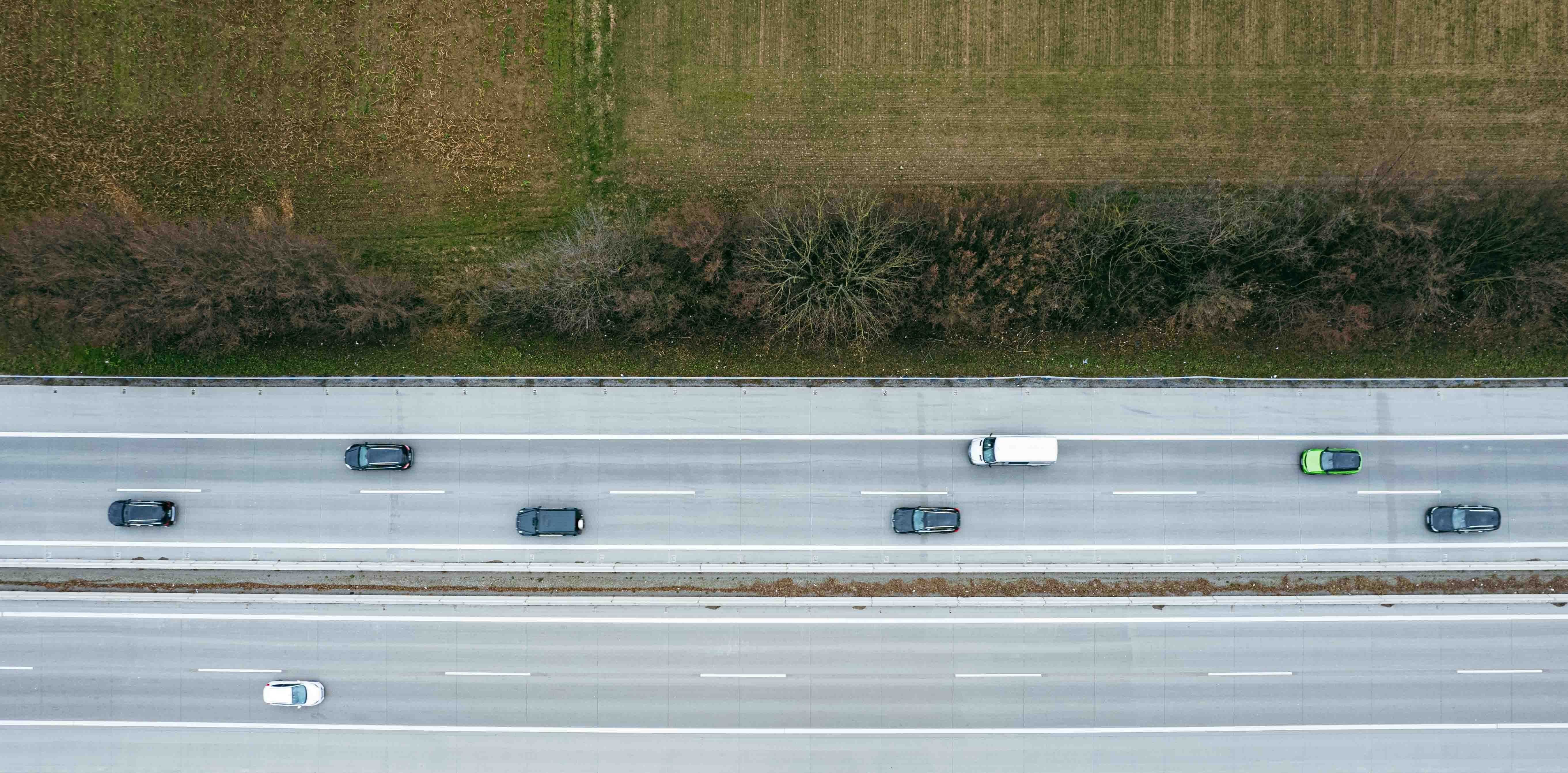 An aerial view of a motorway alongside a green field