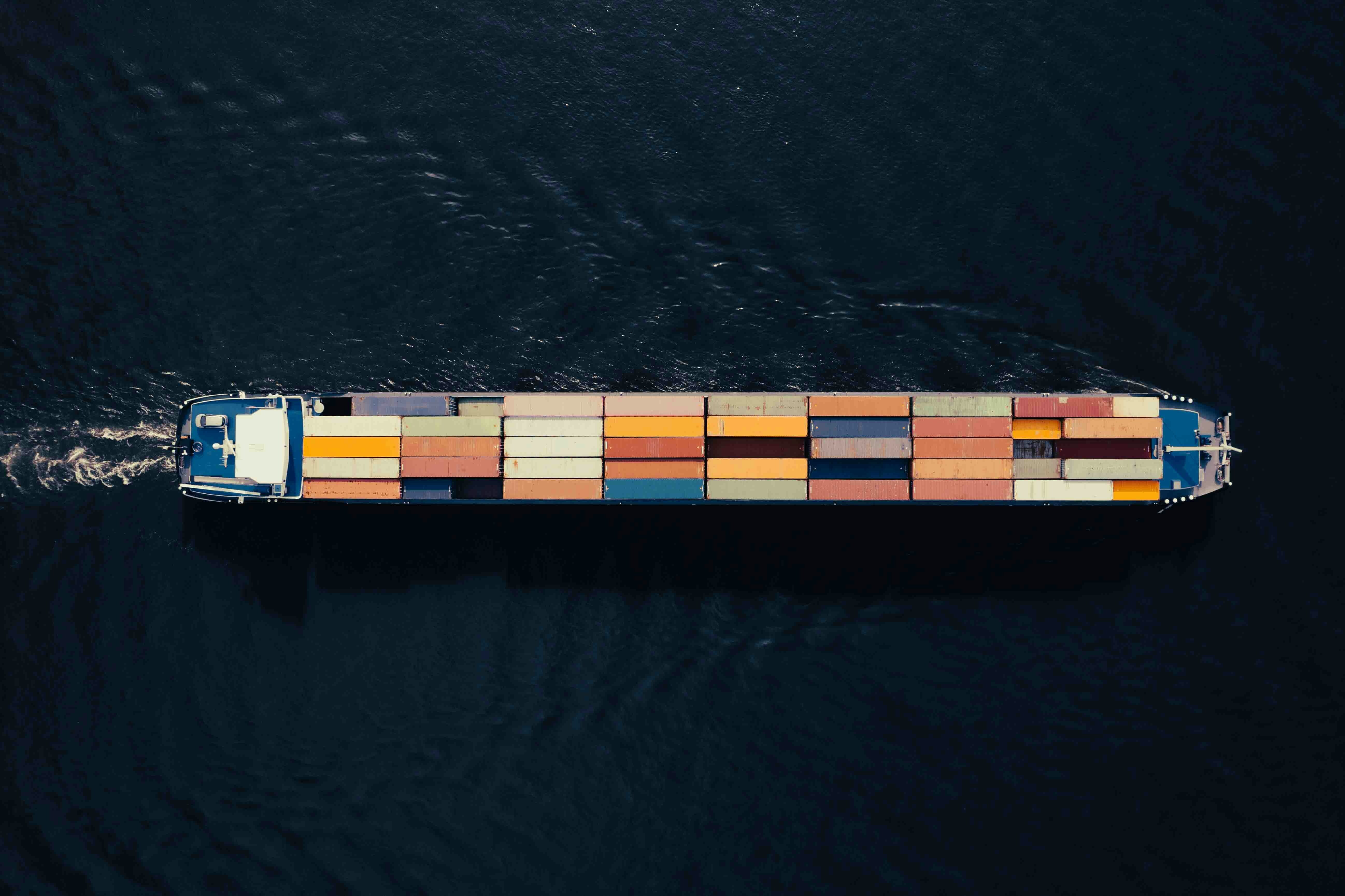 An aerial view of a lone merchant ship at sea carrying cargo