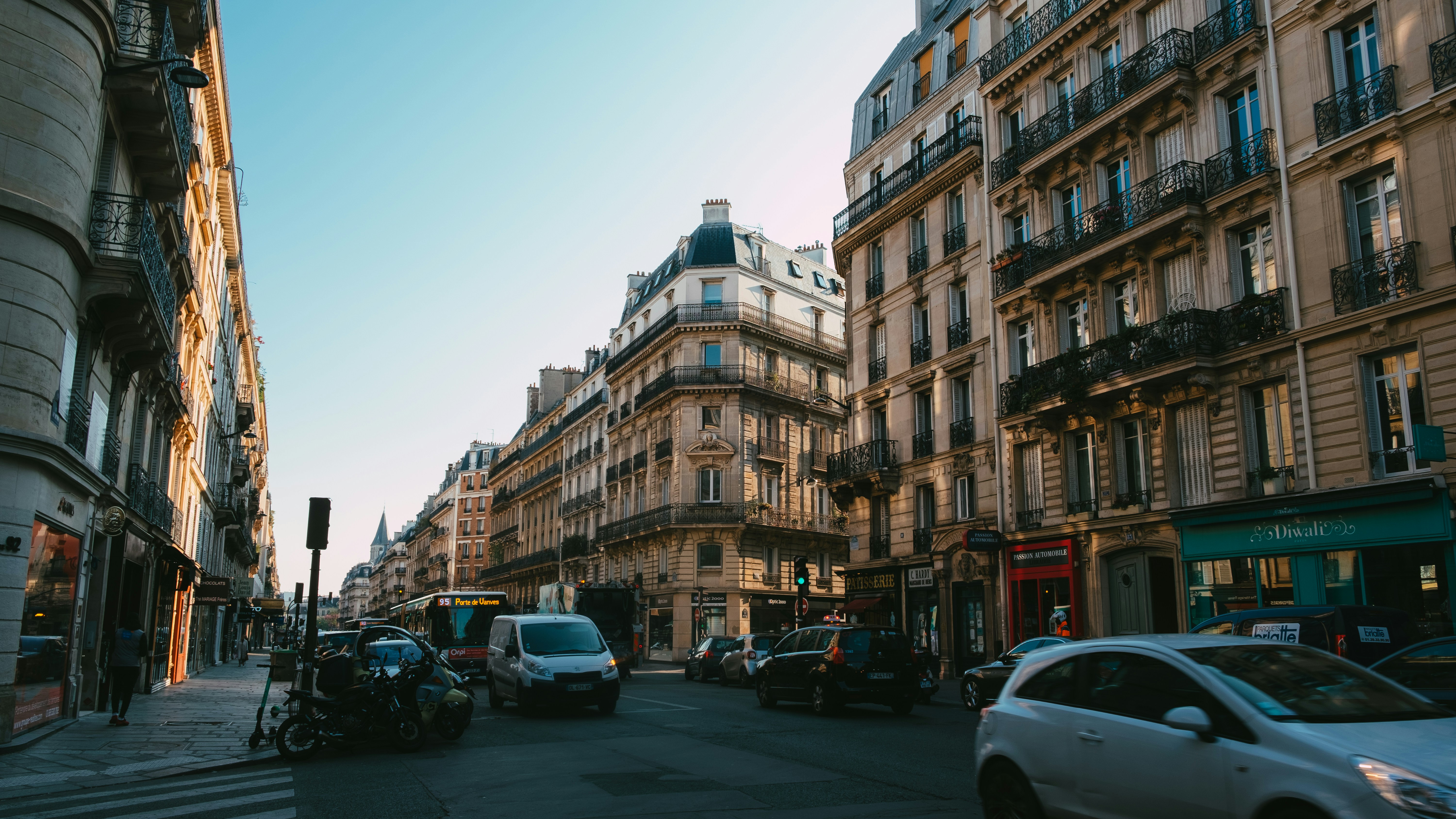 A street in Paris featuring mixed-use buildings and a variety of vehicles