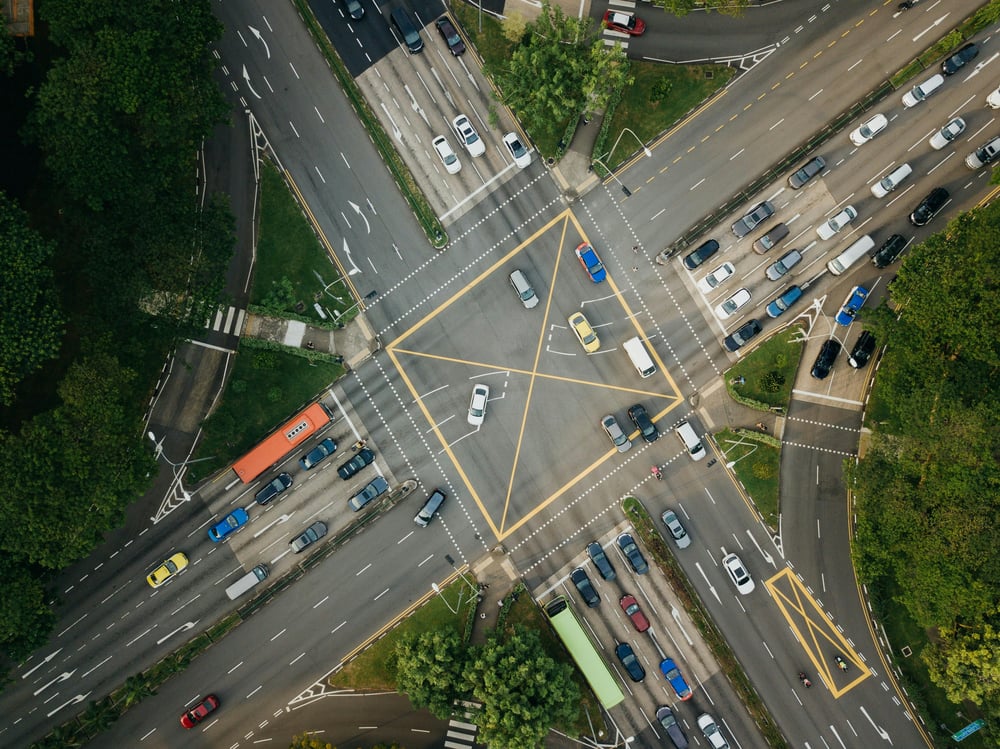 An aerial view of a crossroads junction in a town with traffic