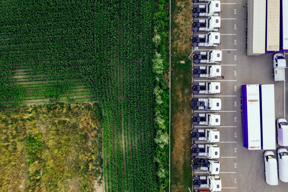 An aerial view of a fleet of parked commercial vehicles next to a field