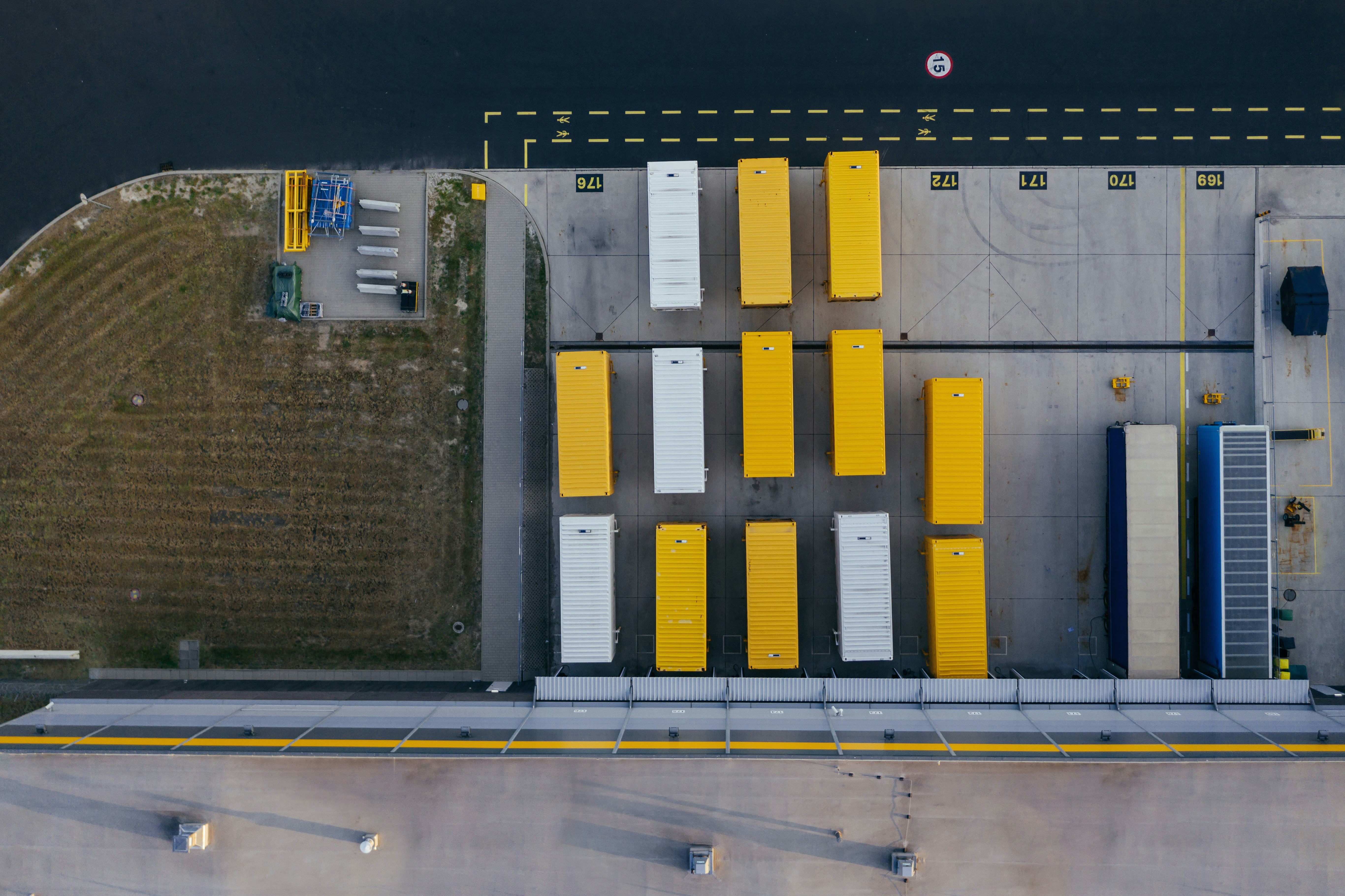 An aerial view of yellow and white shipping containers placed in rows