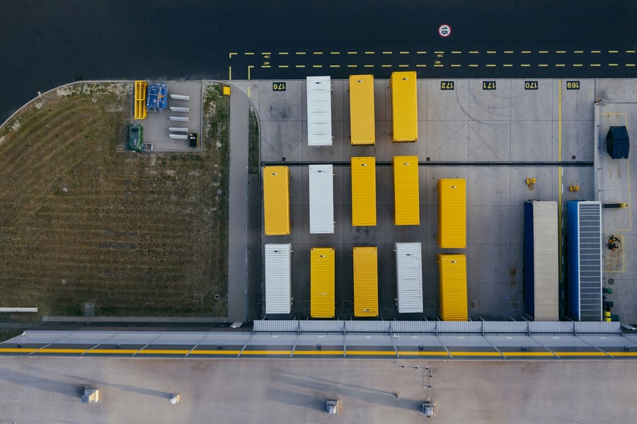 An aerial view of yellow and white shipping containers placed in rows