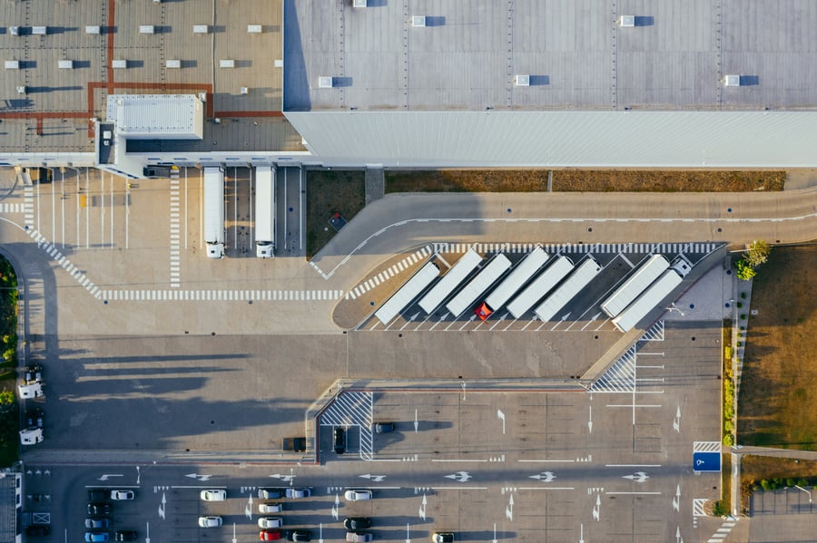 An aerial shot of the outside of a factory and the on-site car park with several vehicles